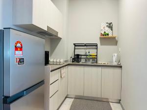 a small kitchen with a refrigerator in a room at Jesselton Quay - Suite 1 by Staycation Suites KK in Kota Kinabalu