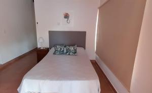 Un dormitorio pequeño con una cama con dos almohadas. en Karina House, en Jardín América