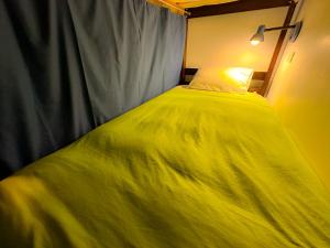 Una cama con una manta amarilla encima. en Tucan Hostel, en Cusco