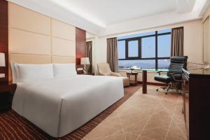 una camera d'albergo con un grande letto bianco e una scrivania di Crowne Plaza Beijing International Airport, an IHG Hotel a Shunyi