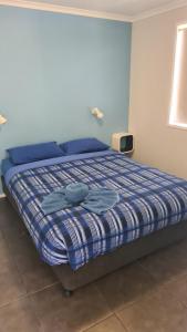 a bedroom with a bed with a blue and white comforter at Banana Coast Caravan Park in Coffs Harbour