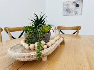 Una mesa de madera con una canasta con plantas encima. en Sophisticated City Retreat with All the Comforts, en Wagga Wagga