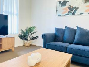 Una sala de estar con un sofá azul y una mesa de café. en Sophisticated City Retreat with All the Comforts, en Wagga Wagga