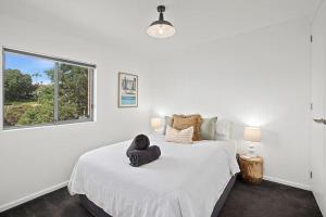 Un dormitorio blanco con una cama con una toalla. en 'Seabreeze Escape' in Prime Jetty Location! en Coffs Harbour