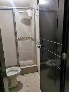 a bathroom with a toilet and a glass shower stall at GIGAHOUSE in Baños