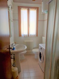 uma casa de banho com um lavatório, um WC e uma janela. em Apartments in Eraclea 44135 em Eraclea