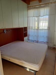 uma cama vazia num quarto com janela em Apartments in Eraclea 44135 em Eraclea