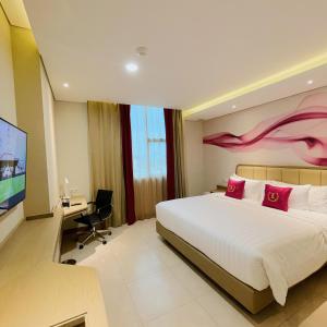 a bedroom with a bed and a desk and a tv at Leedon Hotel & Suites Surabaya in Surabaya