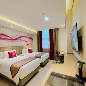 Habitación de hotel con 2 camas y TV de pantalla plana. en Leedon Hotel & Suites Surabaya, en Surabaya