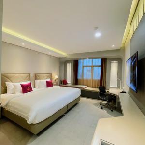 Habitación de hotel con cama grande y escritorio. en Leedon Hotel & Suites Surabaya, en Surabaya