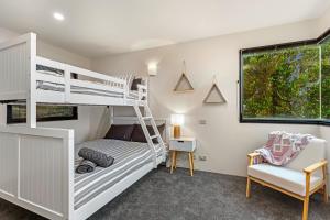 ein Schlafzimmer mit einem Etagenbett und einem Stuhl in der Unterkunft Orton Oceanview Luxury Retreat in Ocean Grove