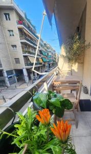 アテネにあるNewly Renovated Apartment 7 min walk from Acropolisのオレンジの花と椅子が飾られたバルコニーと建物