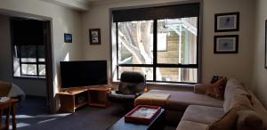 a living room with a couch and a flat screen tv at Peak 105 in Mount Buller