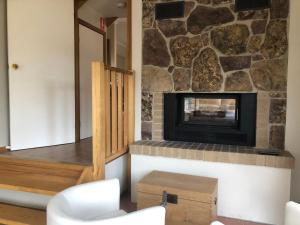 a living room with a fireplace and a stone wall at Day Dream Cottage in Merrijig