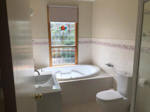 baño con bañera, aseo y ventana en Day Dream Cottage en Merrijig