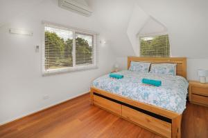 a bedroom with a bed and two windows at Jarrah Lodge in Merrijig