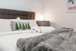 Elkhorn 17 - Mt Buller Village في ماونت بولر: سرير أبيض مع بطانية ووسائد رمادية
