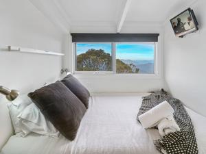 a white bedroom with a bed with a window at SKI View 4 in Mount Buller