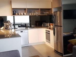 een keuken met witte kasten en een roestvrijstalen koelkast bij Twin Towers 701A in Mount Buller