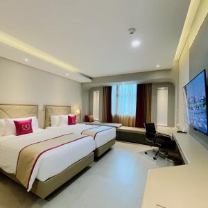 a hotel room with two beds and a flat screen tv at Leedon Hotel & Suites Surabaya in Surabaya