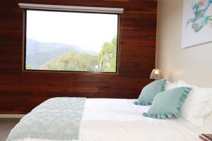 een slaapkamer met een bed en een groot raam bij Woollybutt in Merrijig