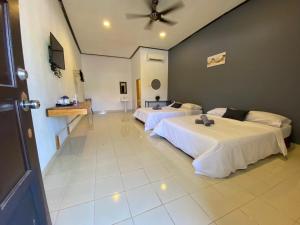 een grote kamer met 2 bedden en een televisie bij Bayu Cenang Inn in Pantai Cenang