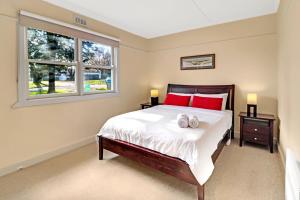 a bedroom with a bed with red pillows and a window at Elouera in Mansfield