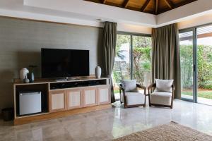 a living room with a television and two chairs at Miskawaan Villa Sila in Mae Nam
