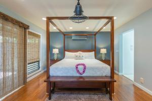 a bedroom with a canopy bed with a pink ribbon on it at Luana Hale in Princeville