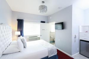 a white bedroom with a white bed and a tv at The Hotel Hollywood in Los Angeles