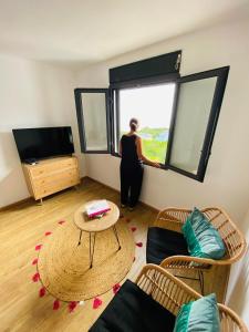 una mujer mirando por una ventana en una sala de estar en Villa Mahot, en Petite Île