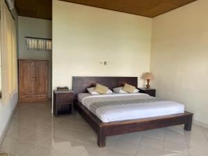 a bedroom with a large bed with a wooden headboard at Lembongan Lux Villas in Klungkung