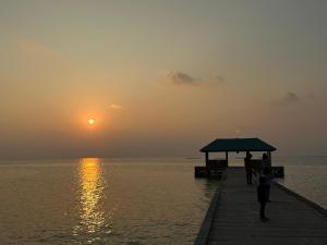 people standing on a pier with the sunset in the background at Sky View by Relax Tours in Dhangethi