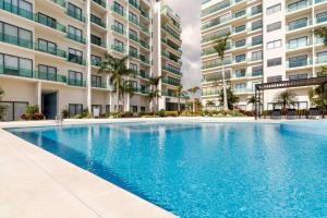 a swimming pool in front of a building at Luxury Condo, 2BR, Fast Internet, Condo Akul in Playa del Carmen