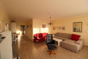 uma sala de estar com um sofá e uma cadeira vermelha em Panorama Whg 57, 4 OG em Cuxhaven