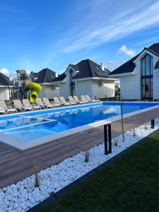 a swimming pool with chairs and a slide in a house at Family Resort Ustka - Domki dwupoziomowe z basenem in Ustka