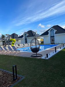 a basket in front of a swimming pool with chairs at Family Resort Ustka - Domki dwupoziomowe z basenem in Ustka