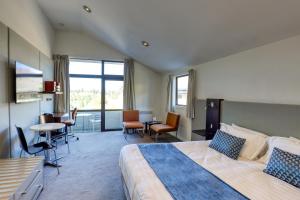 a hotel room with a bed and a table and chairs at Garden Court Suites & Apartments in Queenstown