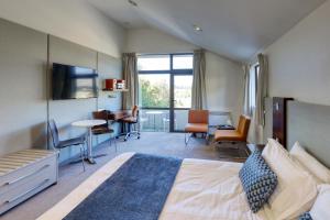 Habitación de hotel con cama, mesa y sillas en Garden Court Suites & Apartments, en Queenstown