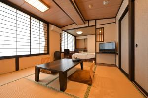 a living room with a table and a room with windows at Ryokan Tamura in Kusatsu