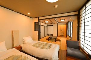 a bedroom with a bed and a chair in a room at Ryokan Tamura in Kusatsu