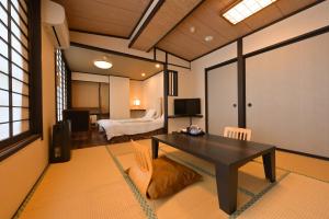 a living room with a table and a bedroom at Ryokan Tamura in Kusatsu