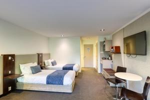 a hotel room with two beds and a television at Garden Court Suites & Apartments in Queenstown