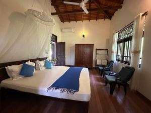 a bedroom with a bed and two chairs in a room at The Bluesky Apartment in Unawatuna