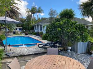 a backyard with a pool and a table and chairs at Colonial House Motel in Kerikeri