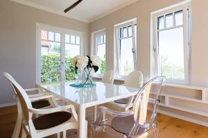 ヴストロにあるHaus am Schilfのガラスのテーブルと白い椅子のあるダイニングルーム