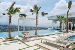 una piscina con due sedie a sdraio e palme di Deluxe Room @ ArtDeco Luxury Hotel & Residence By Parker House a Bandung