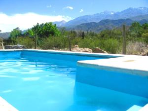 a blue swimming pool with mountains in the background at Las Espuelas Casas de Montaña in Potrerillos