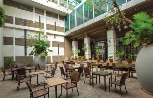 ein Restaurant mit Tischen und Stühlen vor einem Gebäude in der Unterkunft Sparks Life Jakarta, ARTOTEL Curated in Jakarta