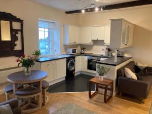 a kitchen and living room with white cabinets and a table at Amazing 2BD Apartment -Upper floors of Dufton Hall in Dufton
